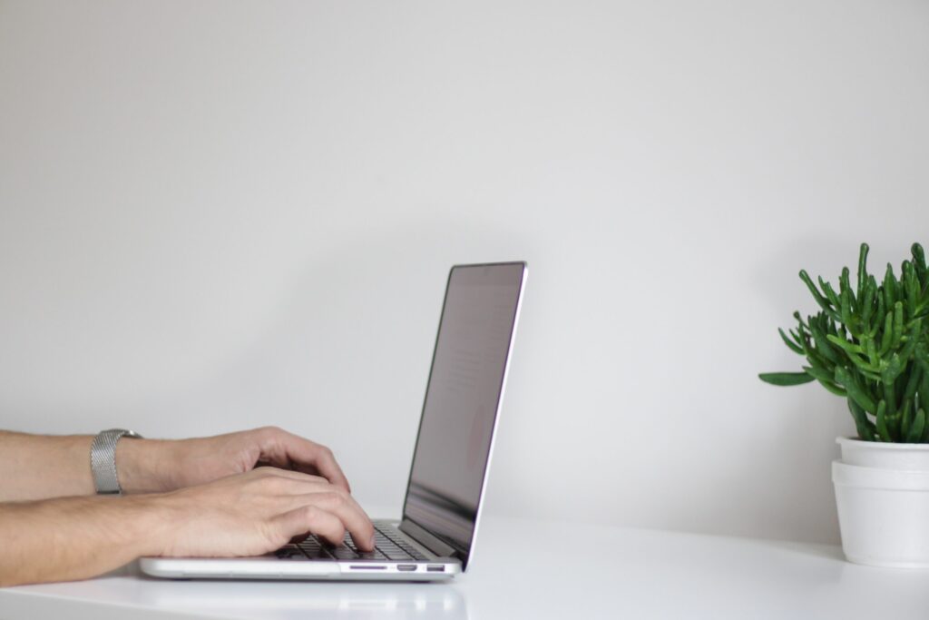 person's hands typing on a laptop